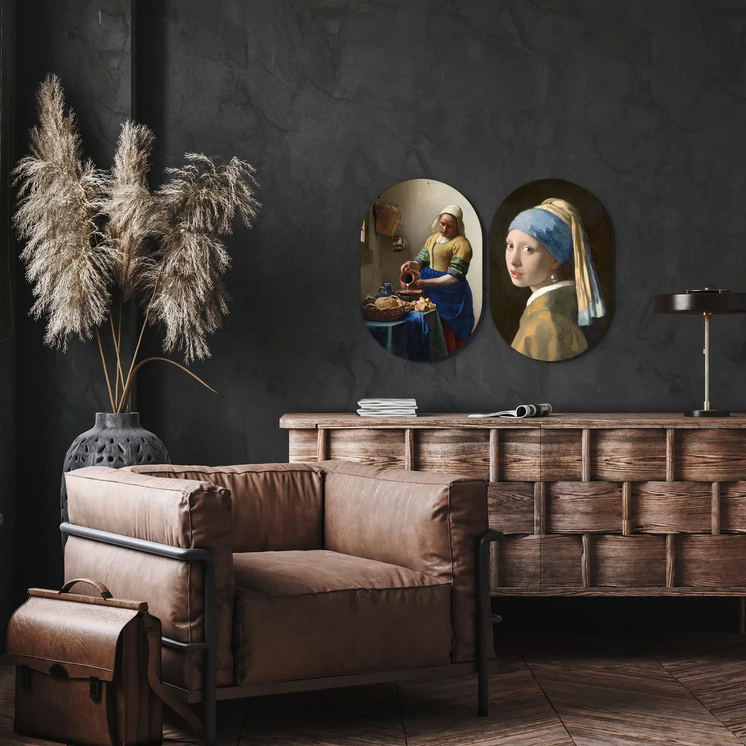 Vermeer tweeluik in twee muurovalen aan een donkere muur bij een leren fauteuil