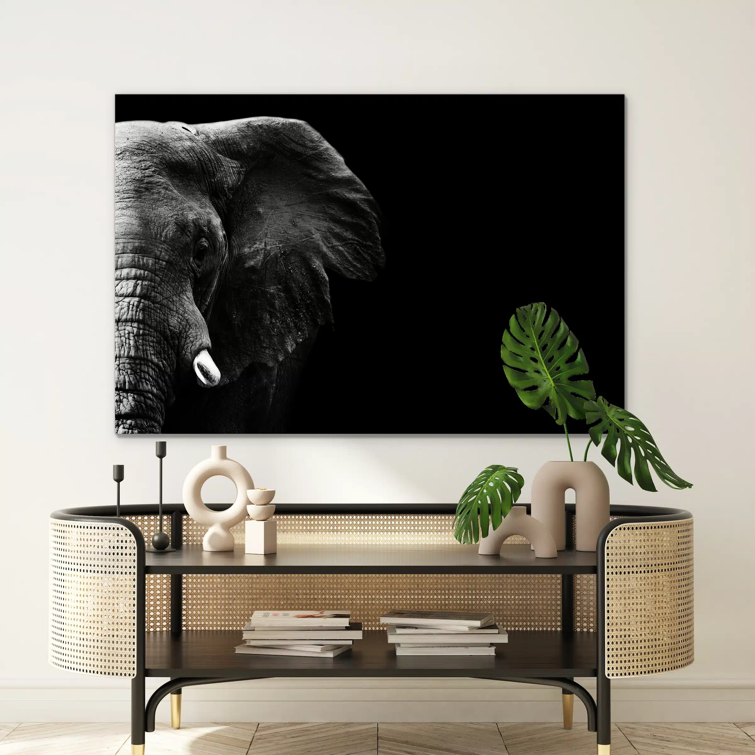 Olifant close-up aan de muur boven een rotan console met een monstera