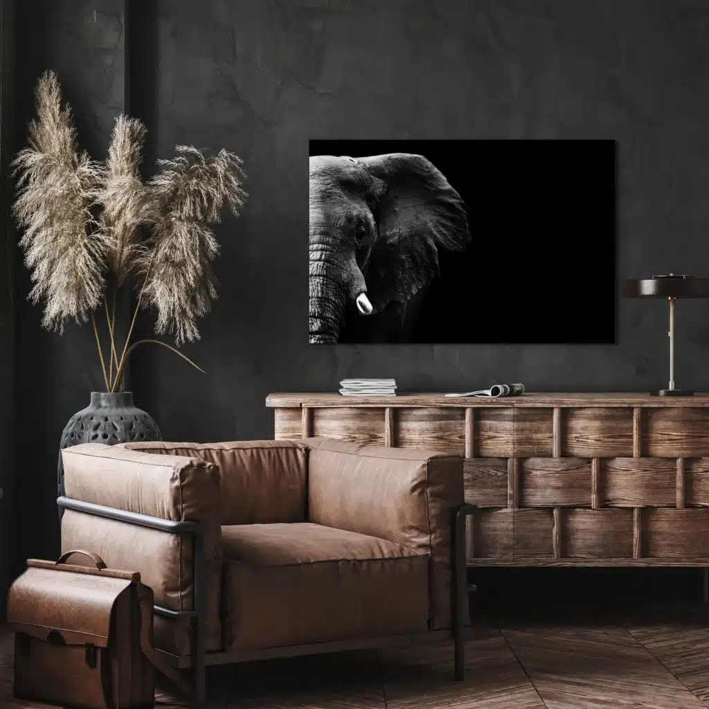 Olifant close-up aan een donkere muur boven een houten dressoir en een leren fauteuil
