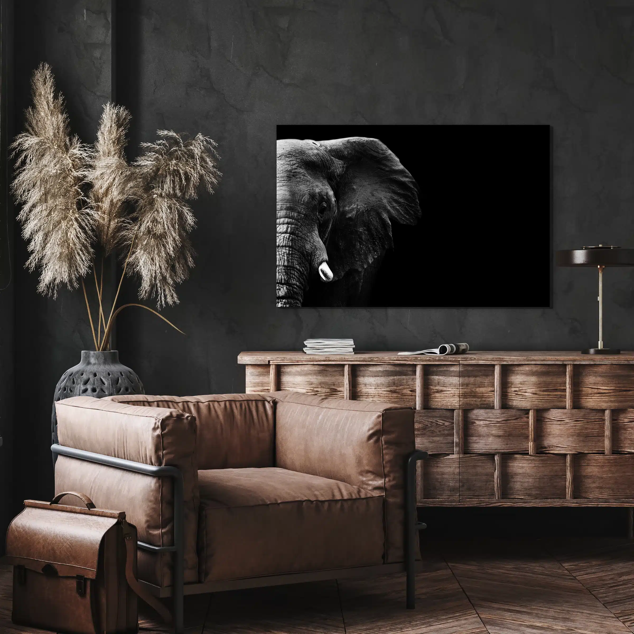 Olifant close-up aan de muur boven een houten dressoir en een leren fauteuil