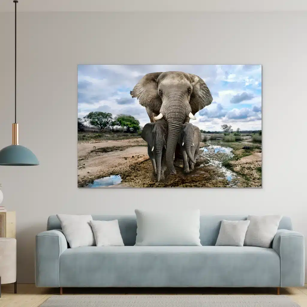Olifantenfamilie aan een lichtgrijze muur boven een lichtblauwe bank met een hanglamp
