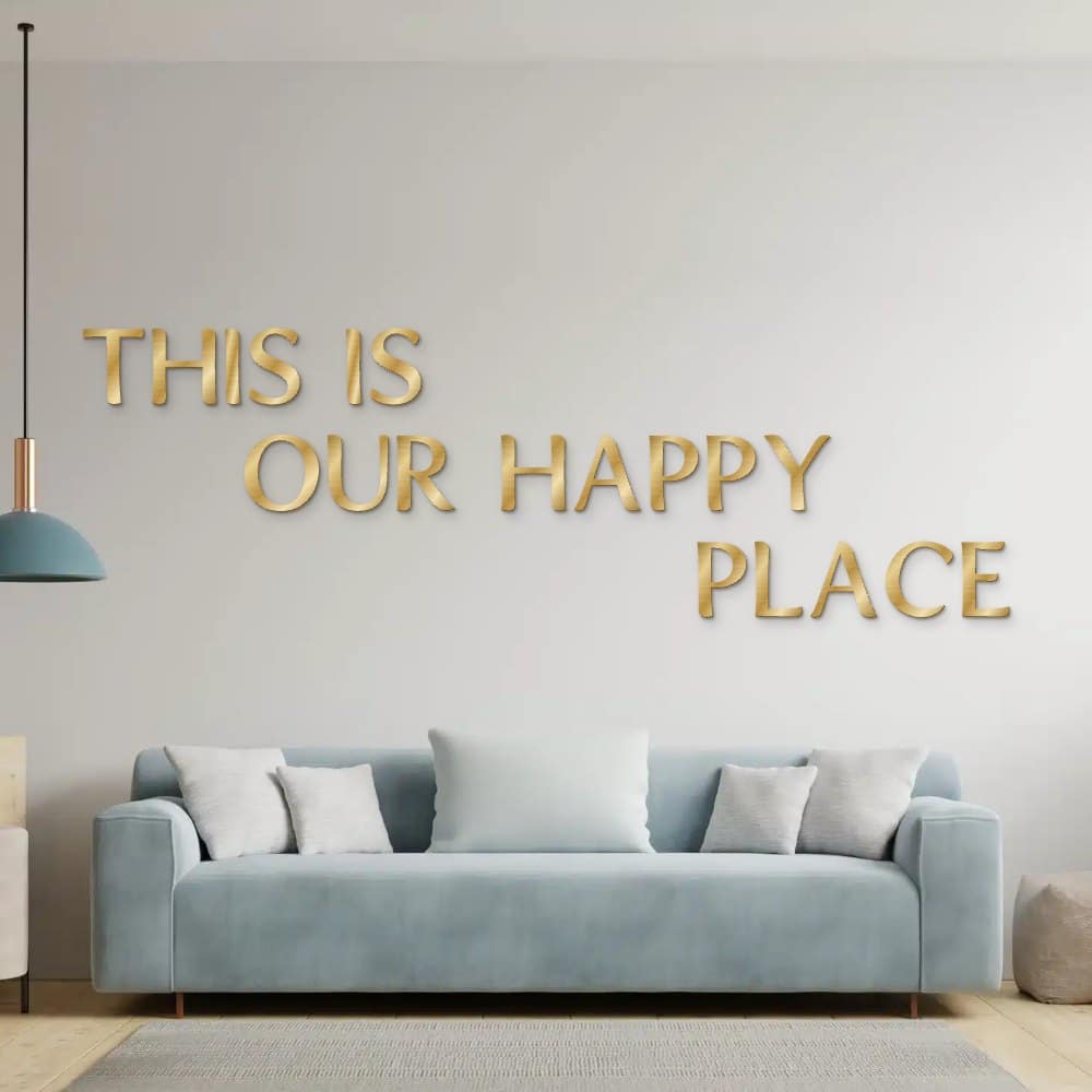 This is our happy place in goud geborsteld aluminium aan de muur boven een bank