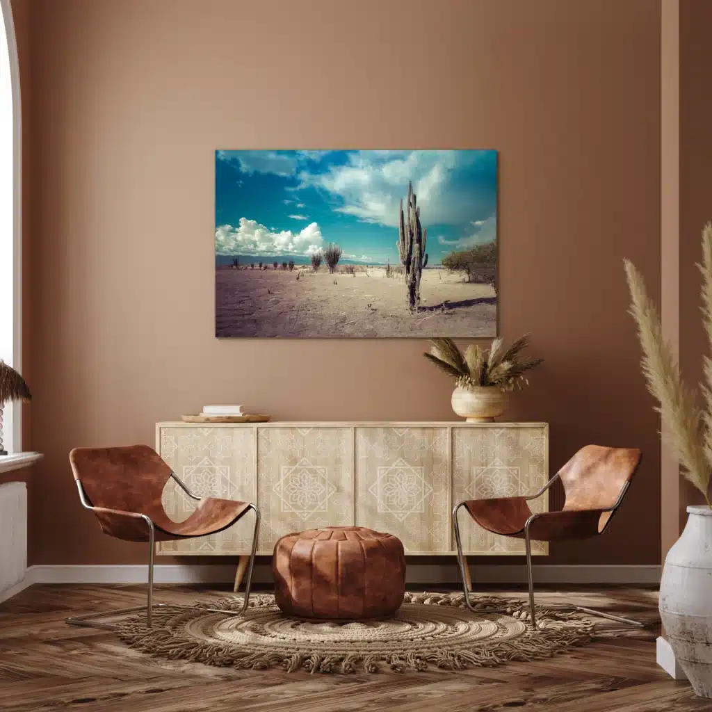 Woestijncactus aan een terracotta muur boven een licht dressoir met twee leren stoelen