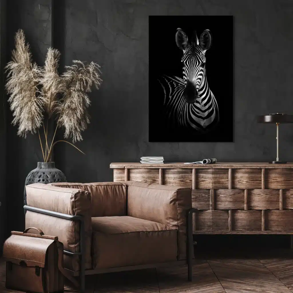 Zebra portret aan een donkere muur boven een houten dressoir en een leren fauteuil
