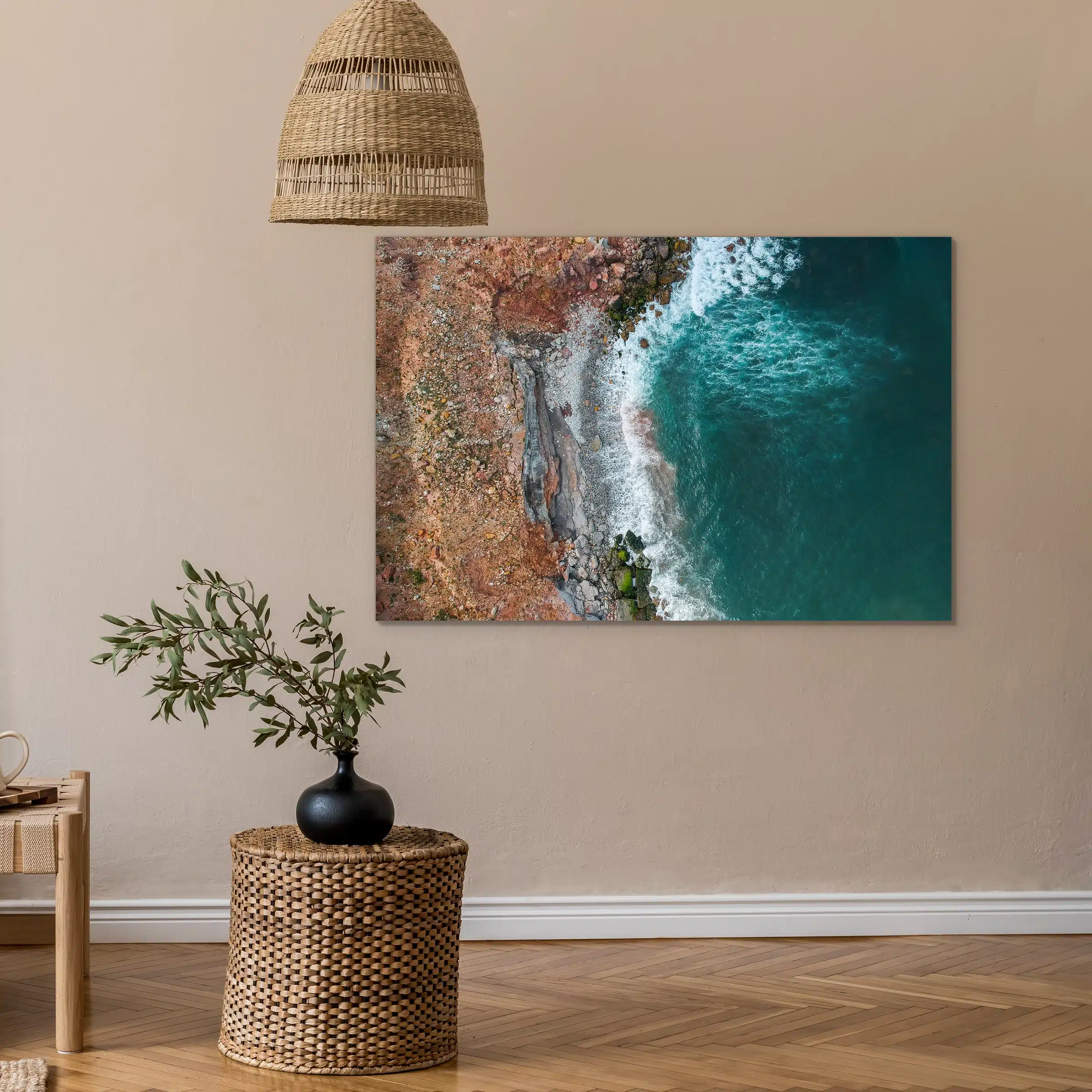 Zee van bovenaf aan een beige muur boven een rieten bijzettafel onder een rieten hanglamp